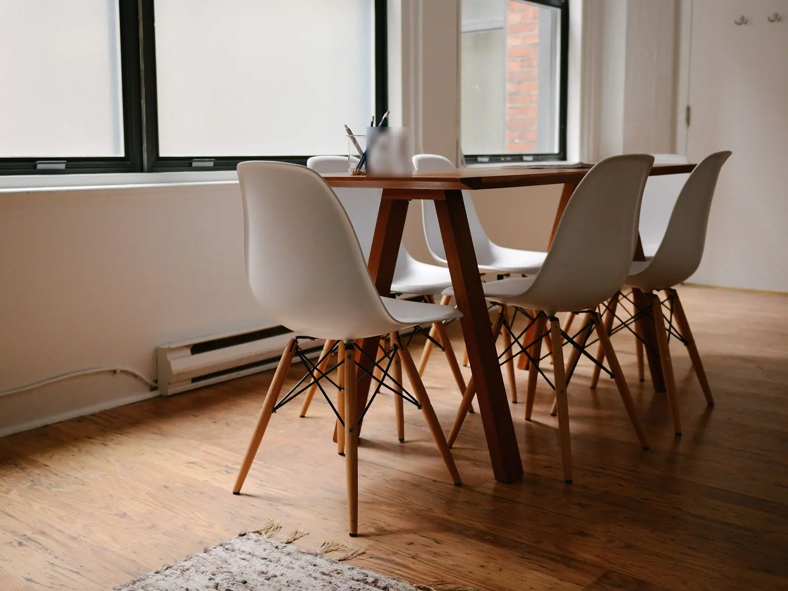 Mesa de madera con seis sillas blancas junto a la ventana