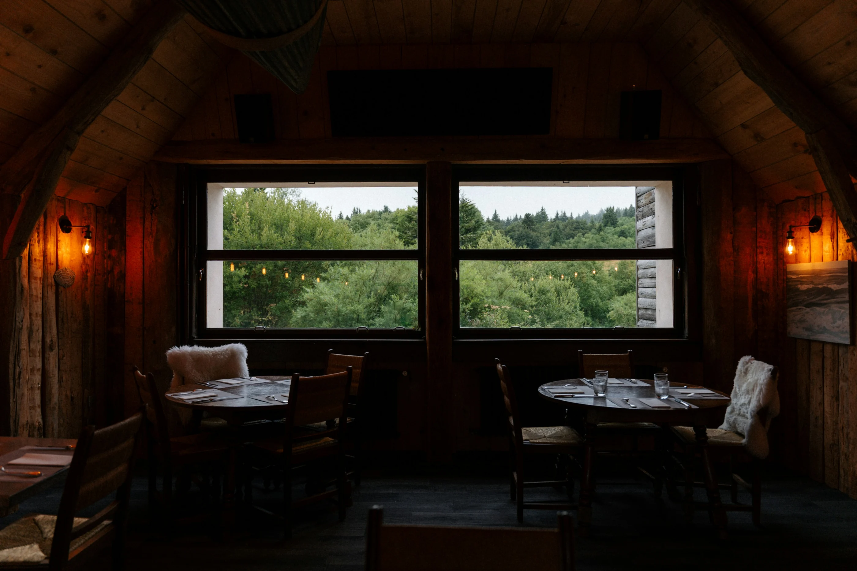 Comedor con vigas de madera y una ventana que da al bosque