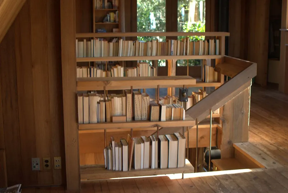 Tramo de madera clara junto a una librería en una casa forrada de tablas