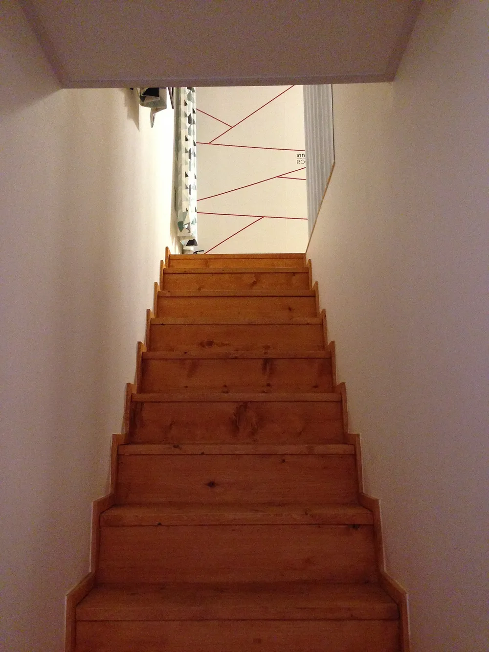 Escalera recta de madera entre dos paredes blancas