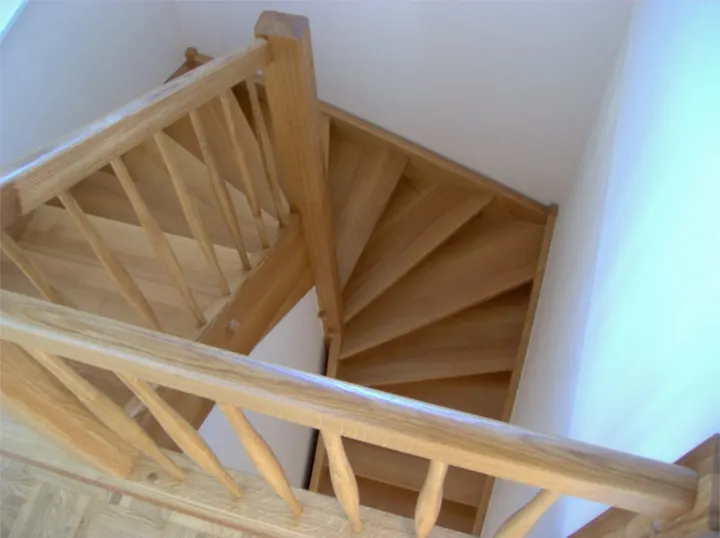 Escalera de madera clara de dos tramos con barandilla de barrotes