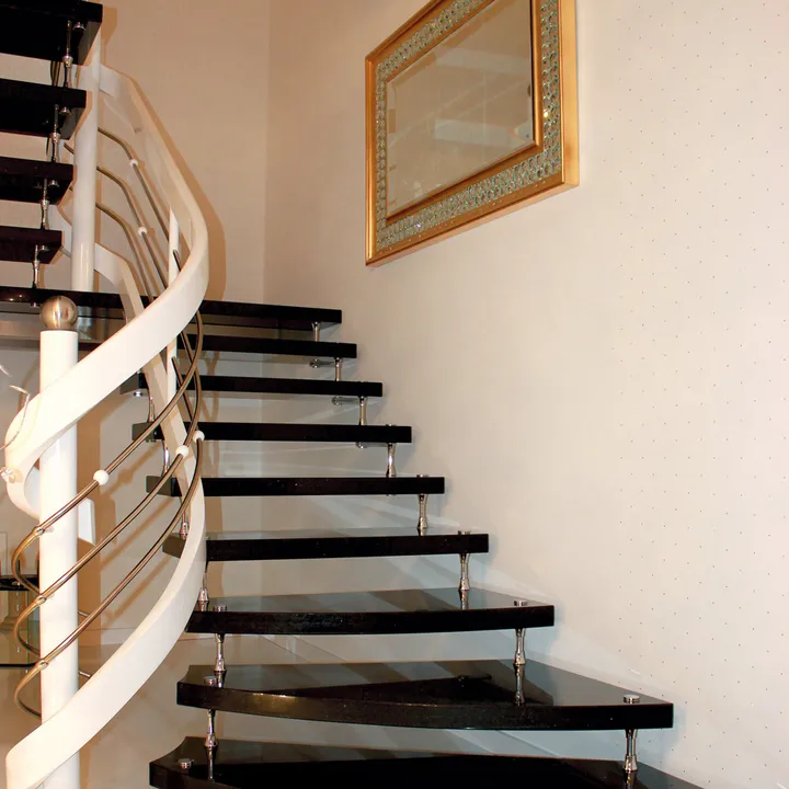 Escalera volada en curva con peldaños oscuros y barandilla de acero